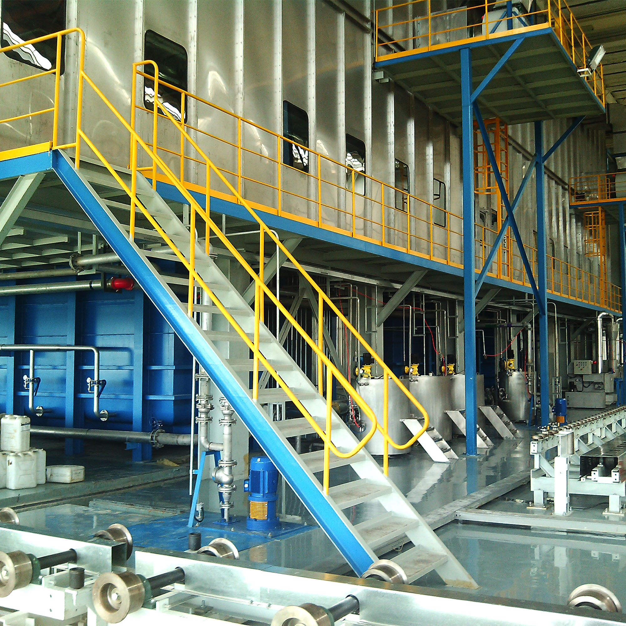 Stainless steel pretreatment tanks with elevated safety-yellow access platform and staircase